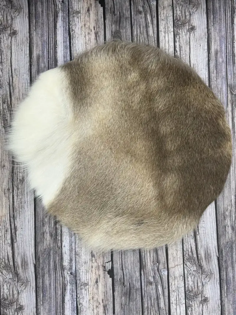 A round reindeer hide seat cover with natural markings on wooden boards